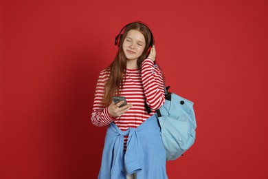 Photo of Teenage girl with smartphone listening to music on red background