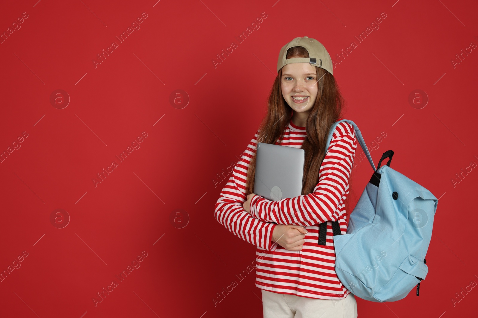 Teenage girl with backpack and laptop on red background. Space for text Photo of Teenage girl with backpack and laptop on red background. Space for text