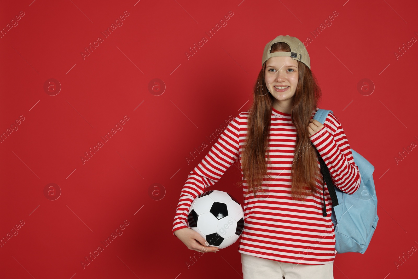 Photo of Teenage girl with soccer ball on red background. Space for text
