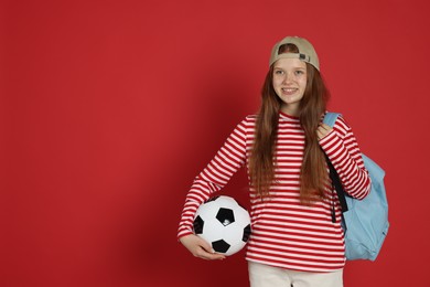 Photo of Teenage girl with soccer ball on red background. Space for text