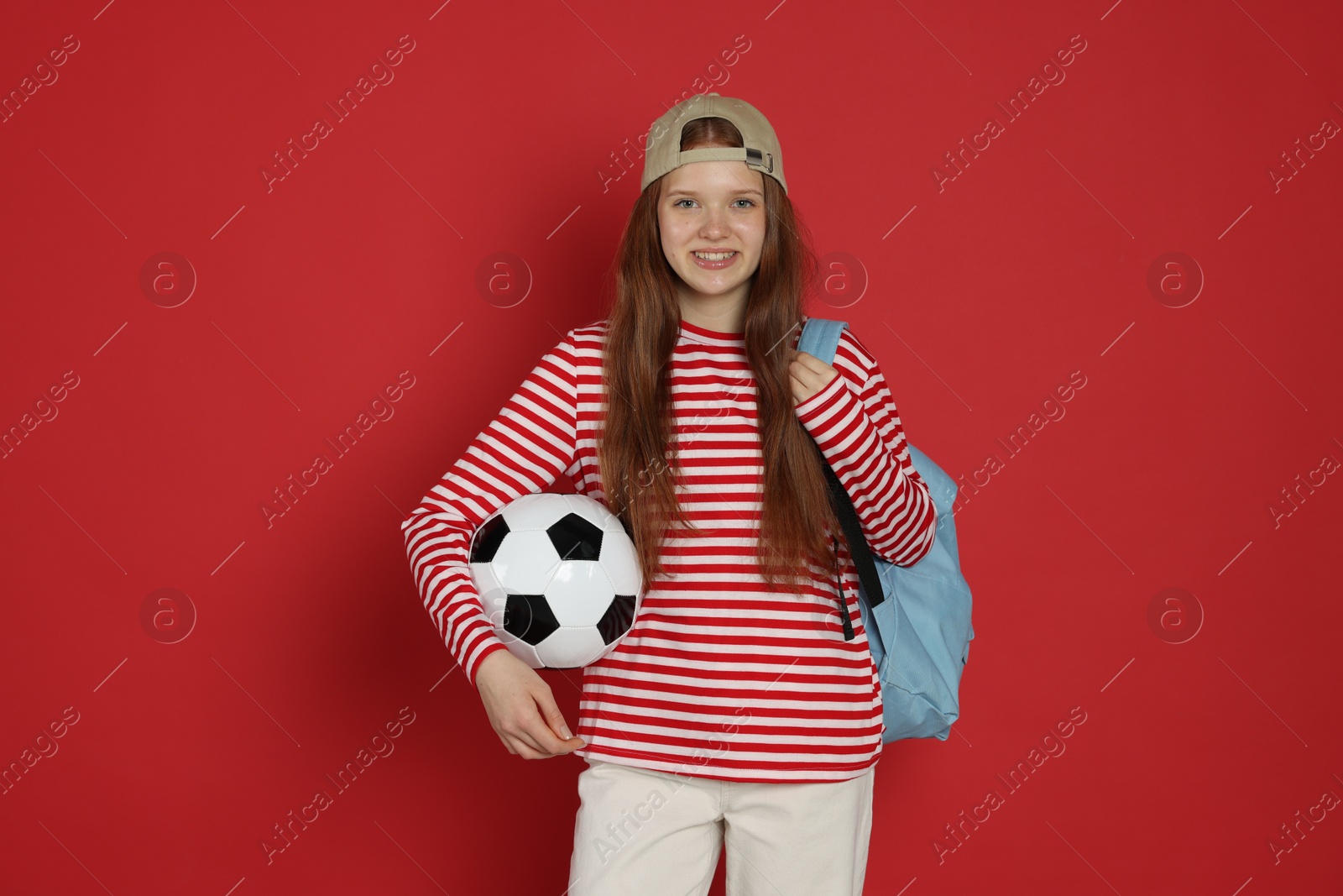 Teenage girl with soccer ball on red background Photo of Teenage girl with soccer ball on red background
