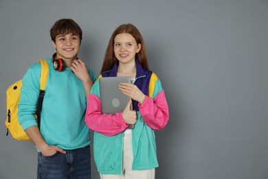 Photo of Teenagers with backpack and laptop on grey background. Space for text