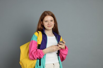 Photo of Teenage girl with smartphone on grey background