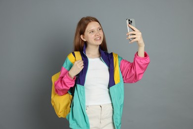 Photo of Teenage girl taking selfie on grey background