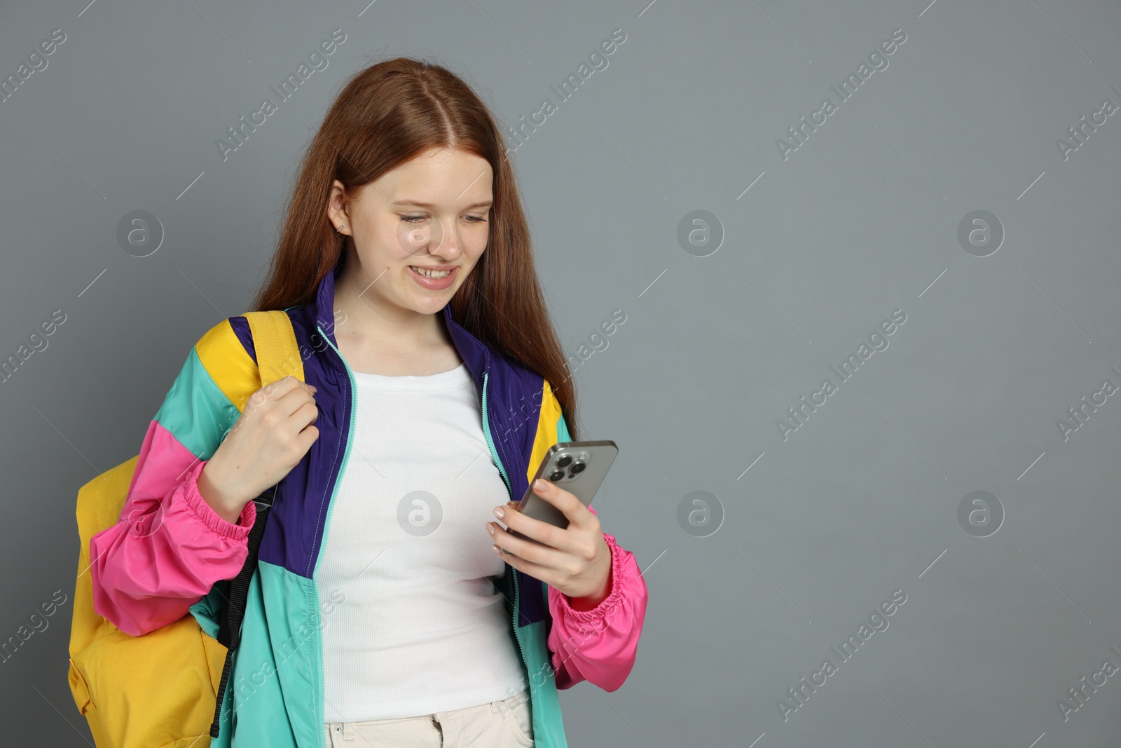 Photo of Teenage girl with smartphone on grey background. Space for text