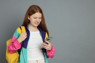 Photo of Teenage girl with smartphone on grey background. Space for text