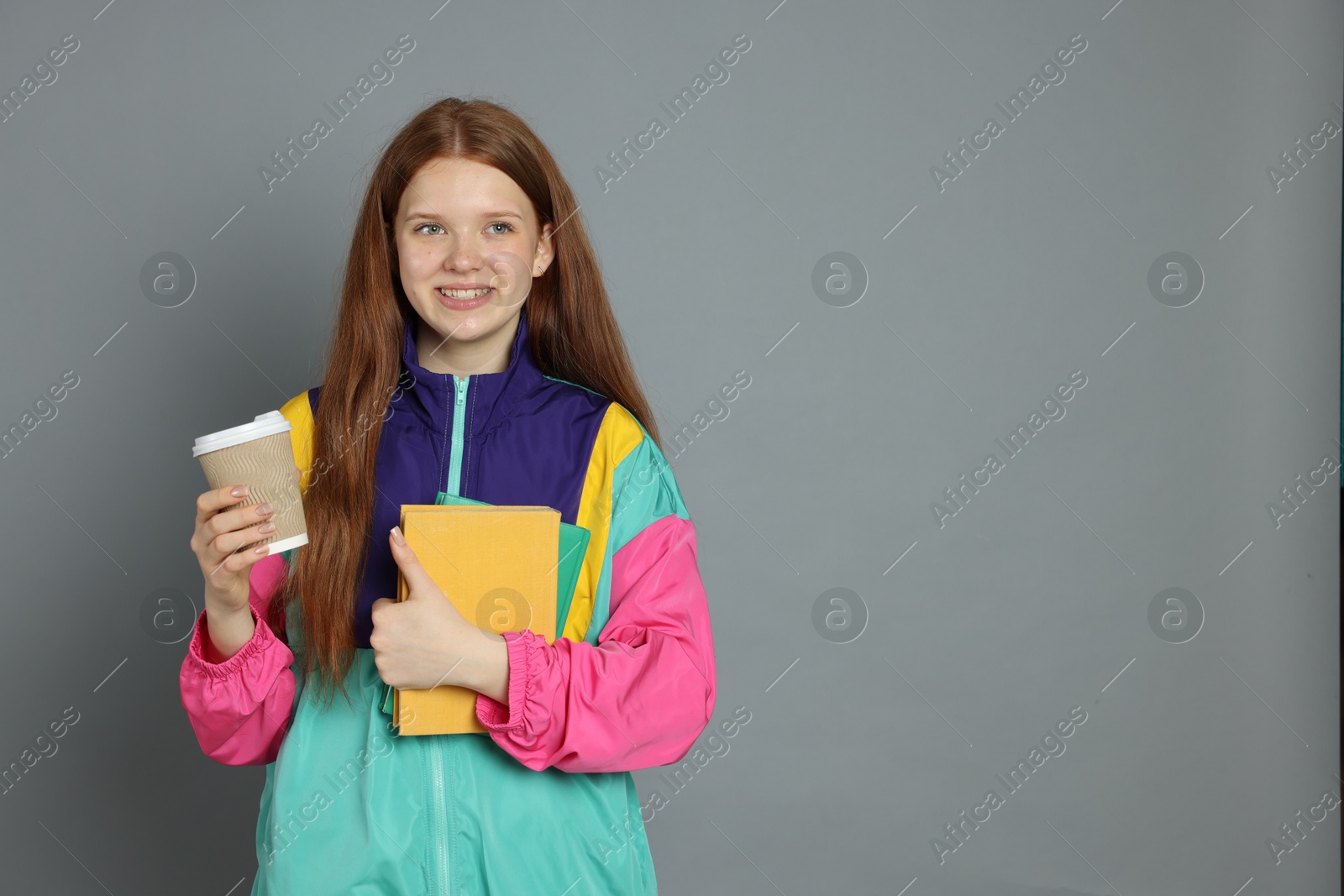 Photo of Teenage girl with drink on grey background. Space for text