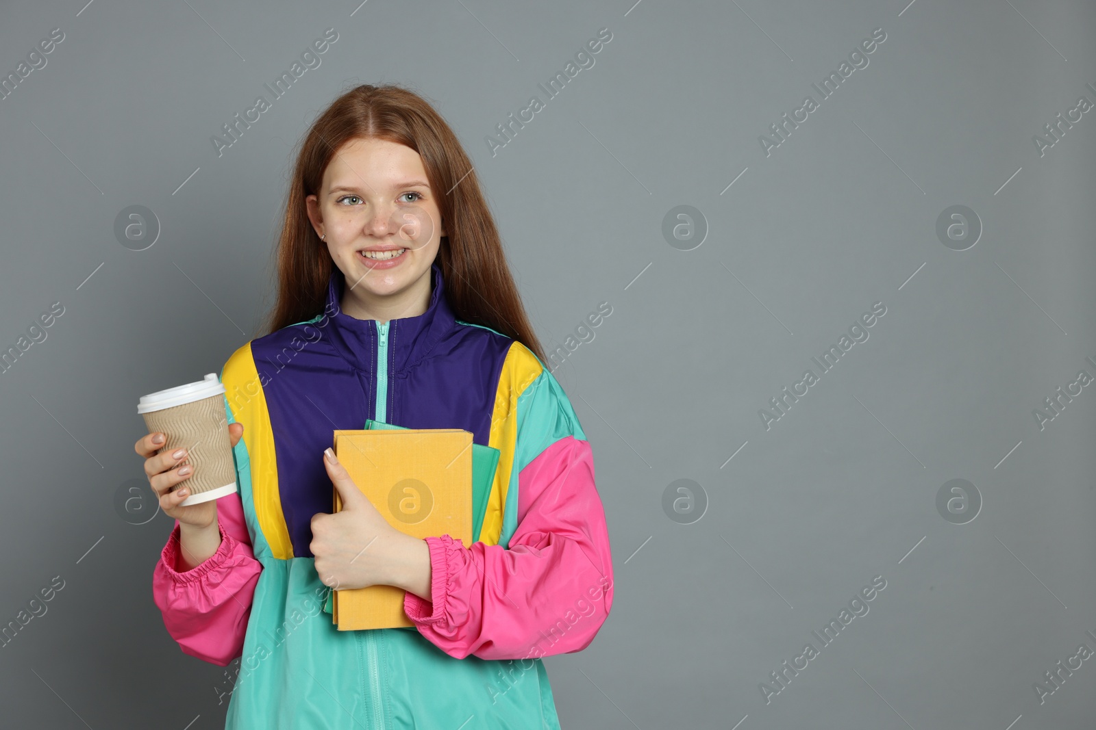 Photo of Teenage girl with drink on grey background. Space for text