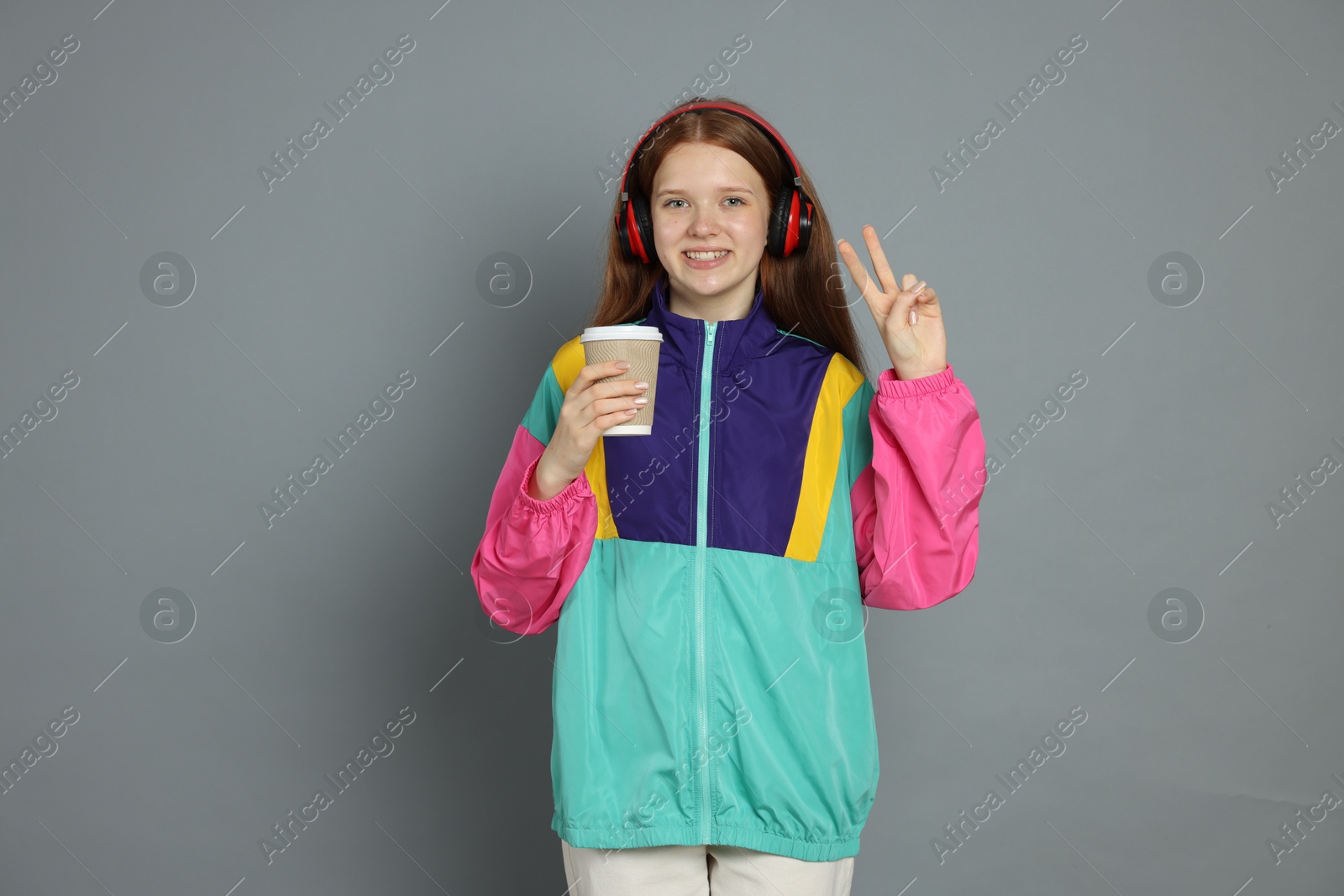 Photo of Teenage girl with drink posing on grey background