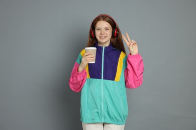 Photo of Teenage girl with drink posing on grey background