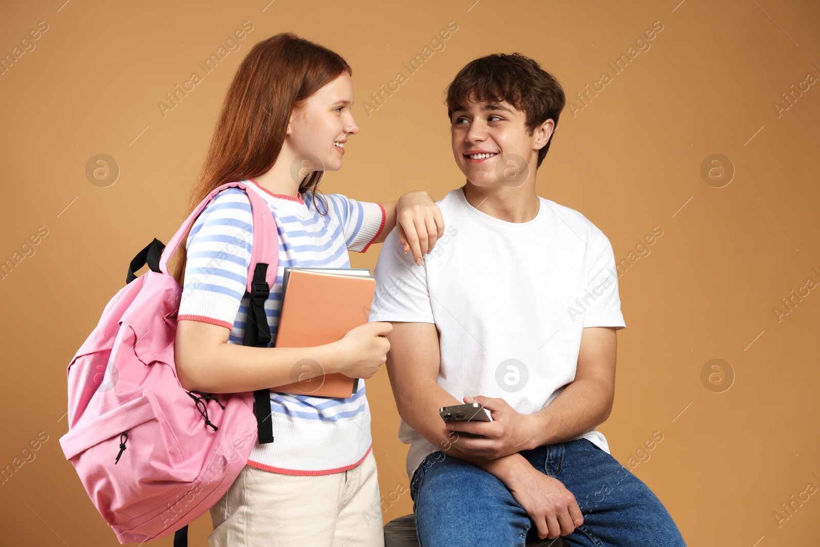 Teenagers with backpack, books and smartphone on brown background Photo of Teenagers with backpack, books and smartphone on brown background