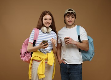 Photo of Teenagers with backpacks and drink on brown background