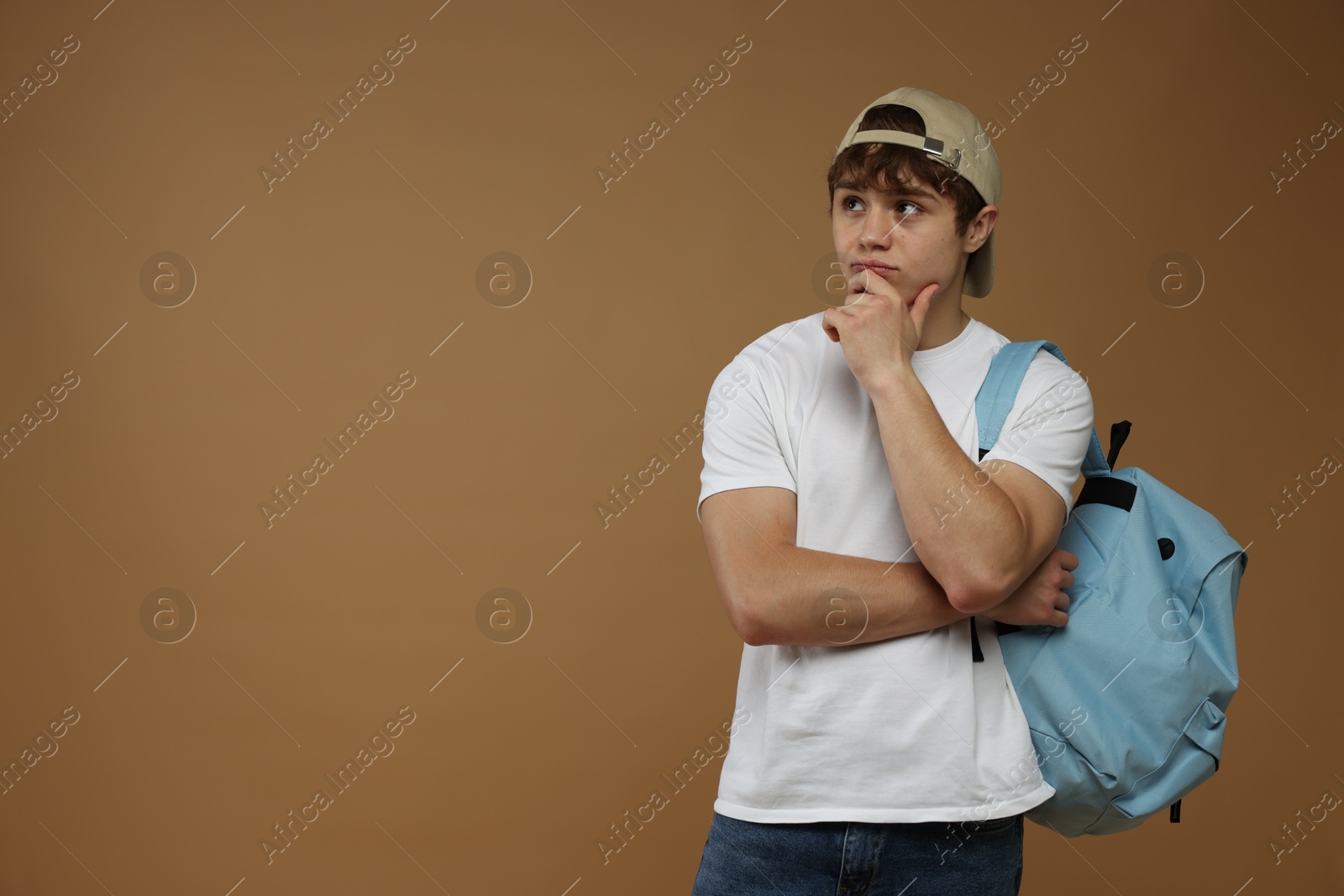 Teenage boy with backpack on brown background. Space for text Photo of Teenage boy with backpack on brown background. Space for text