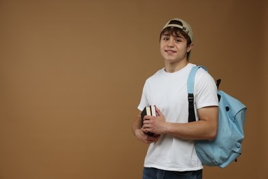 Photo of Teenage boy with backpack and books on brown background. Space for text