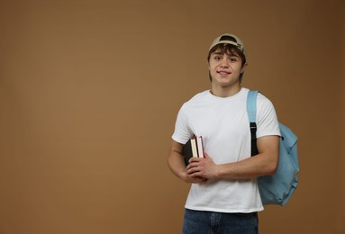 Photo of Teenage boy with backpack and books on brown background. Space for text