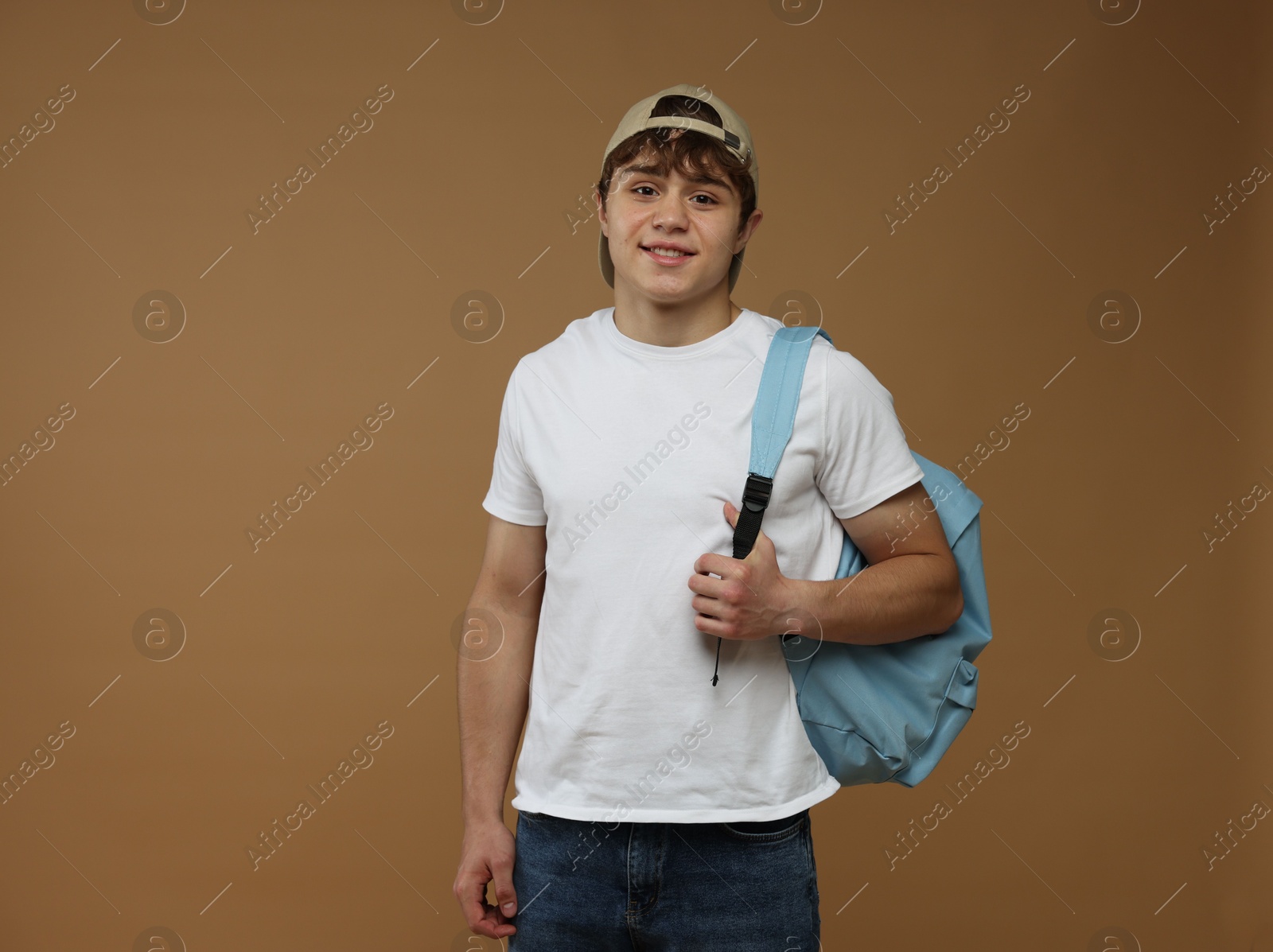 Teenage boy with backpack on brown background Photo of Teenage boy with backpack on brown background