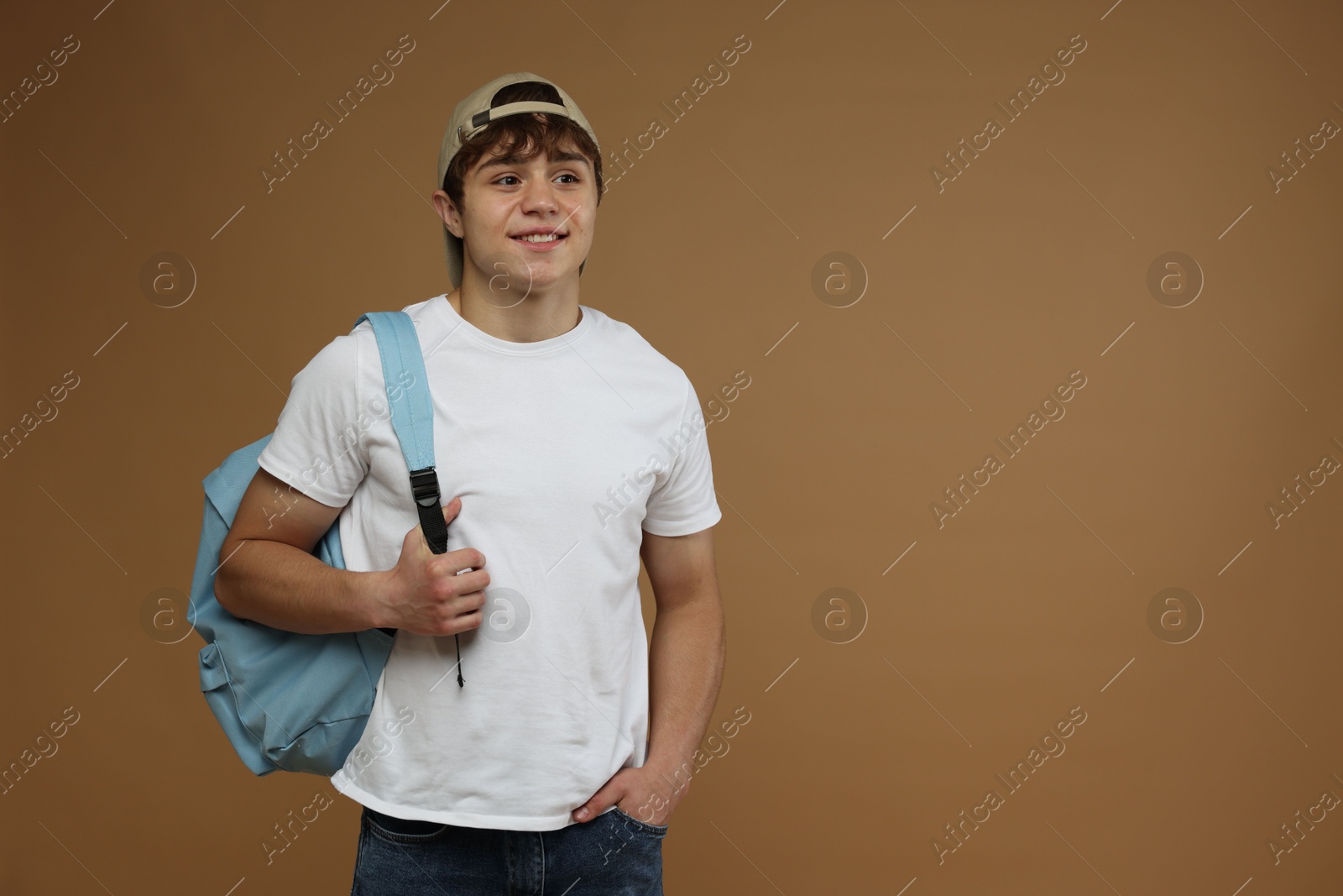 Teenage boy with backpack on brown background. Space for text Photo of Teenage boy with backpack on brown background. Space for text