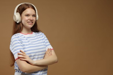 Photo of Teenage girl listening to music on brown background. Space for text