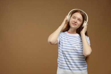 Photo of Teenage girl listening to music on brown background. Space for text