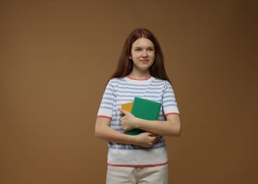Photo of Teenage girl with books on brown background