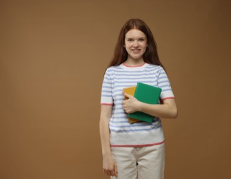 Photo of Teenage girl with books on brown background