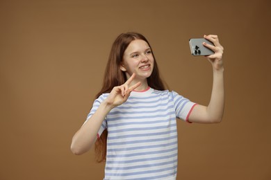 Photo of Teenage girl taking selfie on brown background