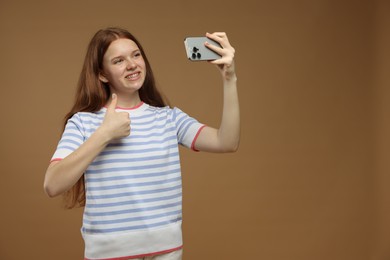 Photo of Teenage girl taking selfie on brown background. Space for text