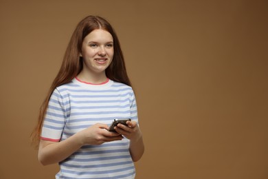 Photo of Teenage girl with smartphone on brown background. Space for text