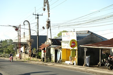 Photo of Bali, Indonesia - May 18, 2025: Different shops and people with scooters on city street