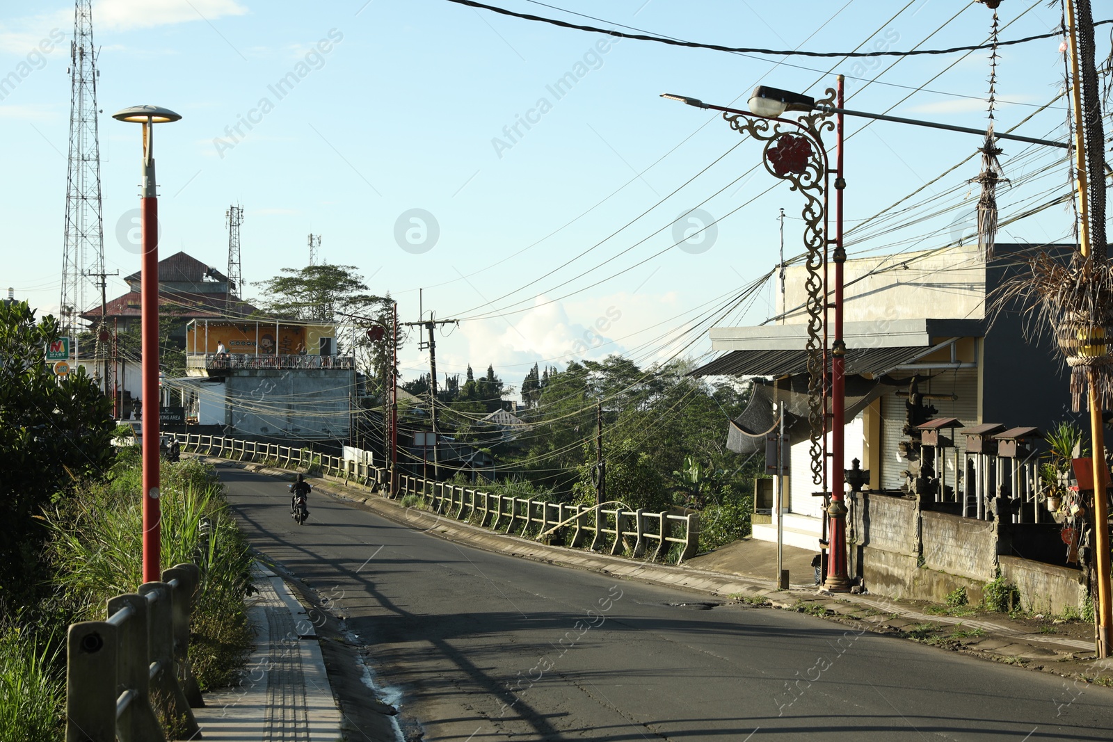 Bali, Indonesia - May 18, 2025: Biker riding across bridge in city Photo of Bali, Indonesia - May 18, 2025: Biker riding across bridge in city