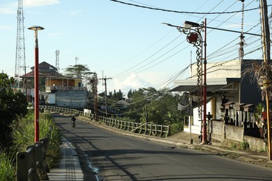 Photo of Bali, Indonesia - May 18, 2025: Biker riding across bridge in city