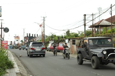 Photo of Bali, Indonesia - May 18, 2025: Cars and scooters on city road