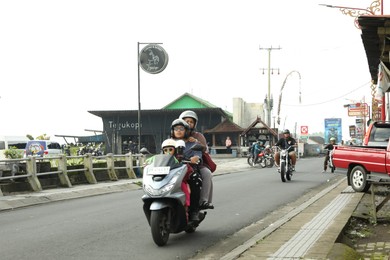 Photo of Bali, Indonesia - May 18, 2025: Bikers on scooters driving in city
