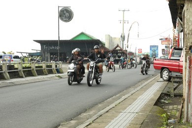 Photo of Bali, Indonesia - May 18, 2025: Bikers on scooters driving in city