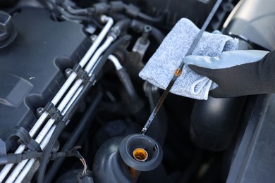 Photo of Worker checking motor oil level in car with dipstick, closeup