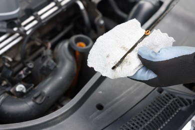 Photo of Worker checking motor oil level in car with dipstick, closeup