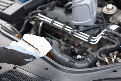 Photo of Worker checking motor oil level in car with dipstick, closeup