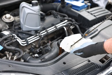 Photo of Worker checking motor oil level in car with dipstick, closeup