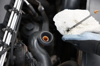 Photo of Worker checking motor oil level in car with dipstick, closeup