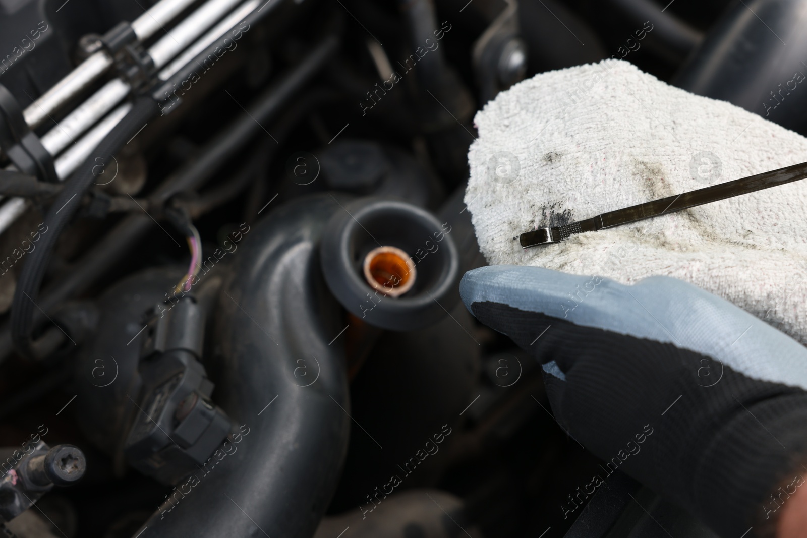 Worker checking motor oil level in car with dipstick, closeup Photo of Worker checking motor oil level in car with dipstick, closeup