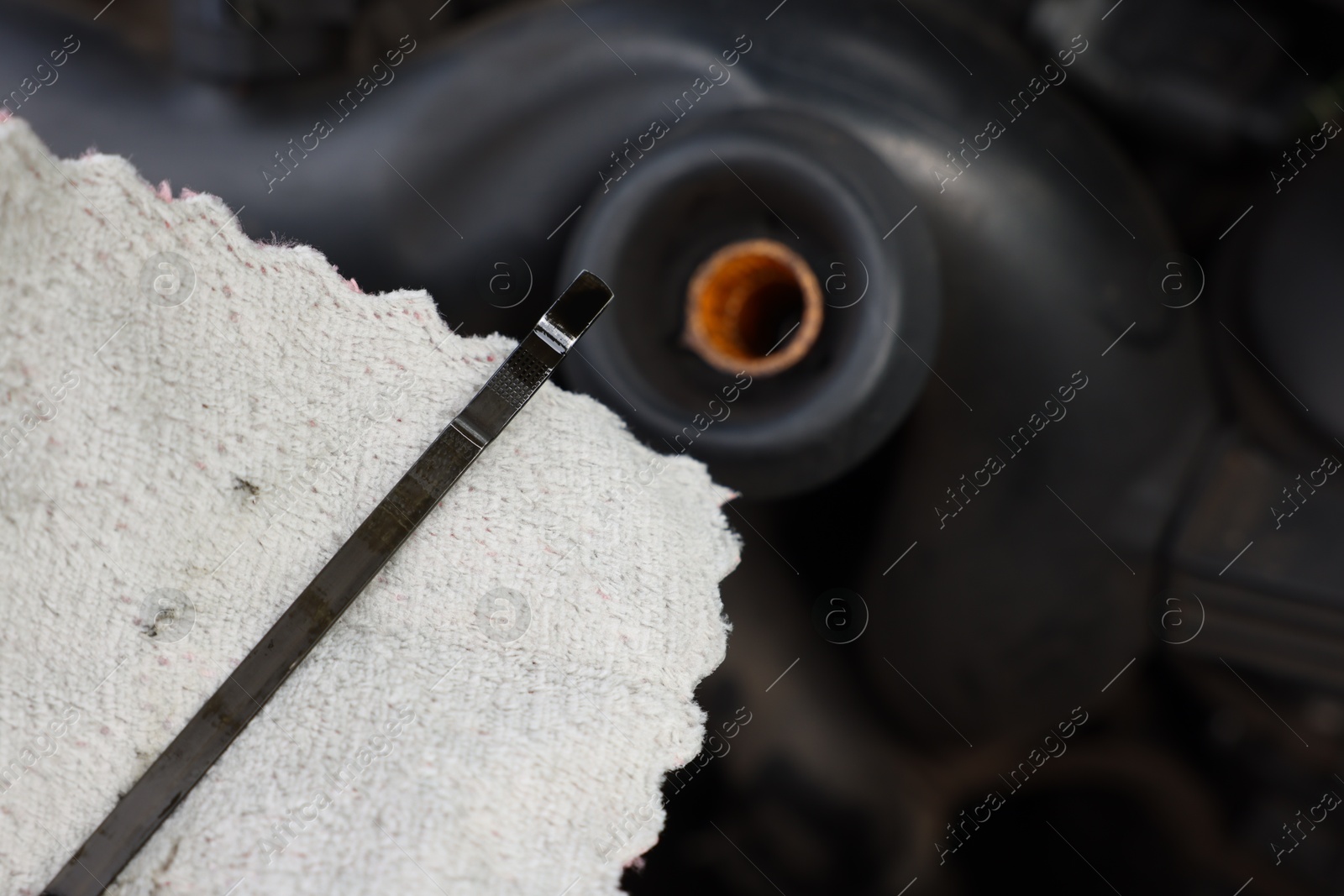 Checking motor oil level. Dipstick and rag near car engine, closeup Photo of Checking motor oil level. Dipstick and rag near car engine, closeup