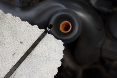 Photo of Checking motor oil level. Dipstick and rag near car engine, closeup