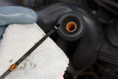 Photo of Worker checking motor oil level in car with dipstick, closeup