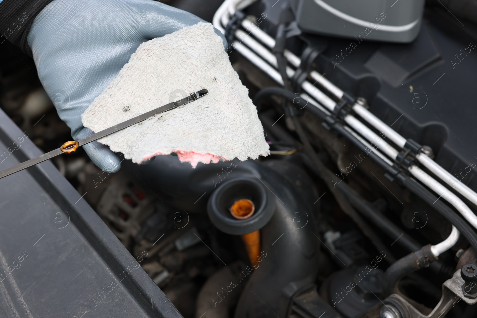 Worker checking motor oil level in car with dipstick, closeup Photo of Worker checking motor oil level in car with dipstick, closeup