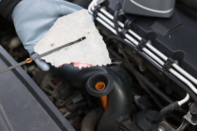 Photo of Worker checking motor oil level in car with dipstick, closeup
