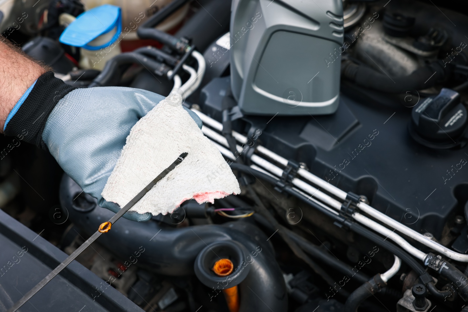 Worker checking motor oil level in car with dipstick, closeup Photo of Worker checking motor oil level in car with dipstick, closeup
