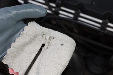 Photo of Worker checking motor oil level in car with dipstick, closeup