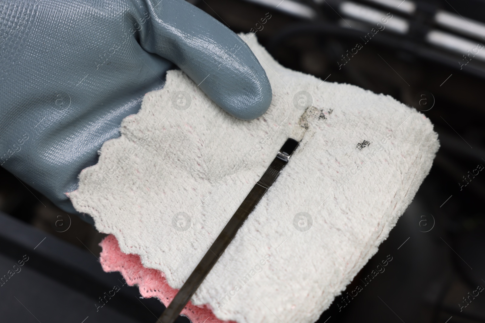 Worker checking motor oil level in car with dipstick, closeup Photo of Worker checking motor oil level in car with dipstick, closeup
