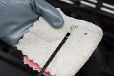 Photo of Worker checking motor oil level in car with dipstick, closeup