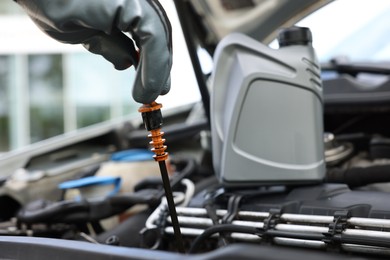 Photo of Worker checking motor oil level in car with dipstick, closeup